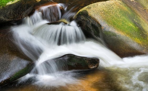 Detail of small beautiful cascade between mossy stones. 