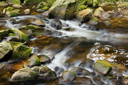 Detail of small beautiful cascade between mossy stones. 