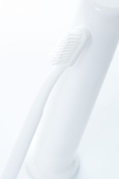 Toothpaste and toothbrush over white. Shallow DOF.