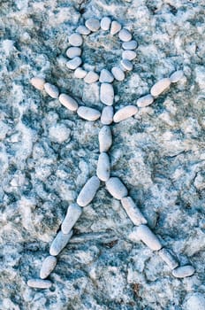 Human figure laid out from pebbles on the textured background
