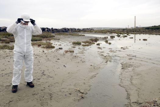 
Worker in a protective suit examining pollution in the water at the industry.