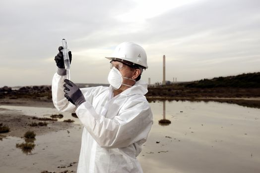 
Worker in a protective suit examining pollution in the water at the industry.