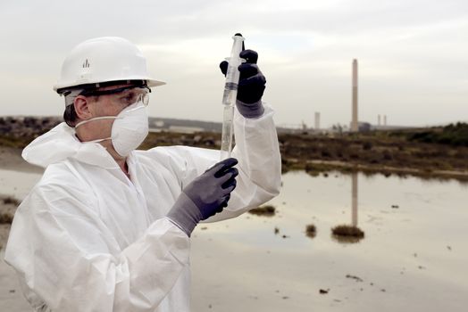 
Worker in a protective suit examining pollution in the water at the industry.