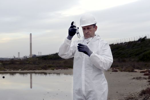 
Worker in a protective suit examining pollution in the water at the industry.