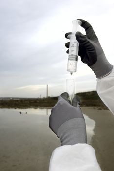 
Worker in a protective suit examining pollution in the water at the industry.