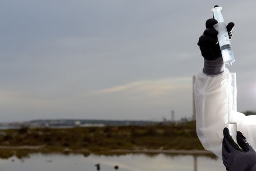 
Worker in a protective suit examining pollution in the water at the industry.