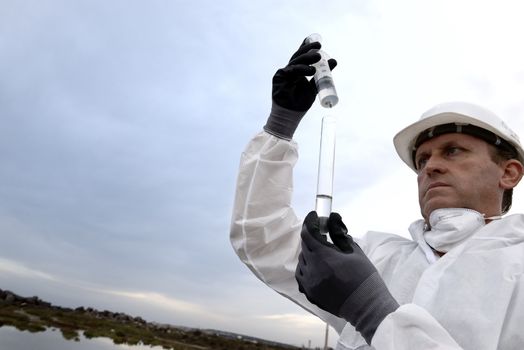 
Worker in a protective suit examining pollution in the water at the industry.