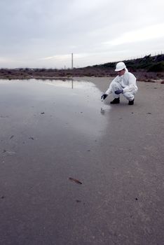 
Worker in a protective suit examining pollution in the water at the industry.