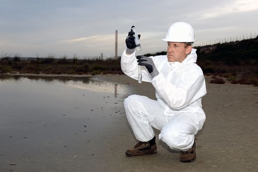 
Worker in a protective suit examining pollution in the water at the industry.