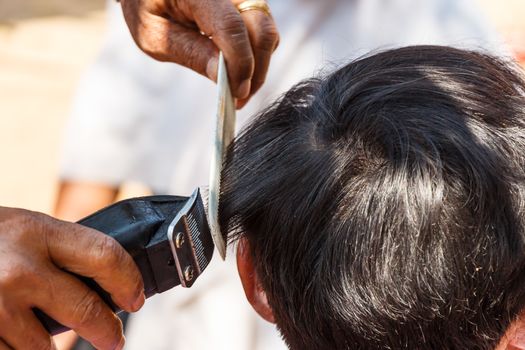 man is cutting hill-man's hair in thailand