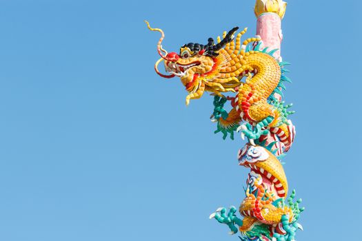 The old statue of gold dragon bind pillar and blue sky