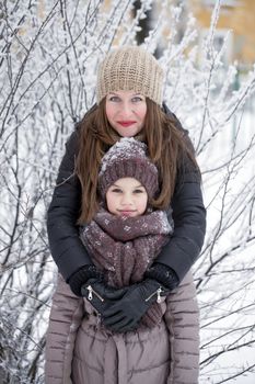 Portrait of a nine year girl with her mother in winter park