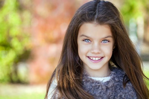 Close up portrait of a beautiful nine year old little girl in autumn park