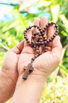 rosary on palm with green color of trees