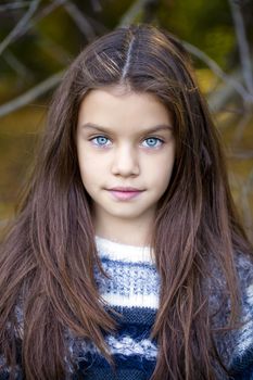 Close up portrait of a beautiful nine year old little girl in autumn park