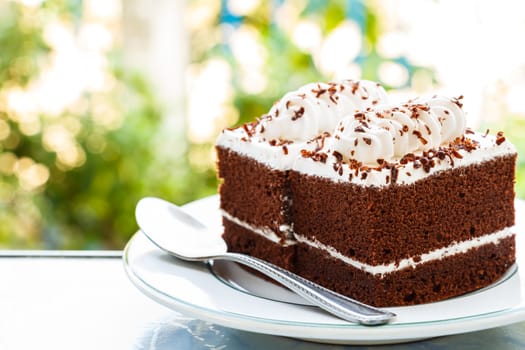 chocolate cakes with white cream on top and spoon on plate and bokeh at background