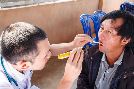 Mobile Health Units in Thailand (Young practitioner is examing patient(hill-man))