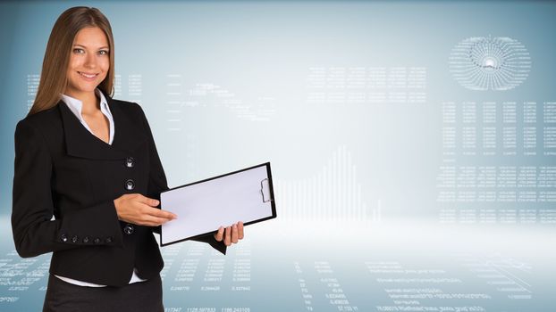 Businesswoman smiling and holding  blank clipboard. Hi-tech graphs as backdrop. Business concept