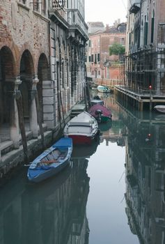 View of Venetian canal in the spring twilight with boats and reflections