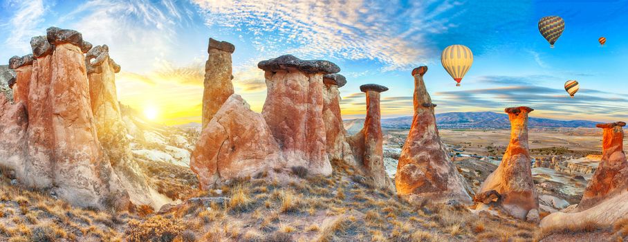 Rocks looking like mushrooms dramatically lit by a sunset in Cappadocia, Turkey. With balloons