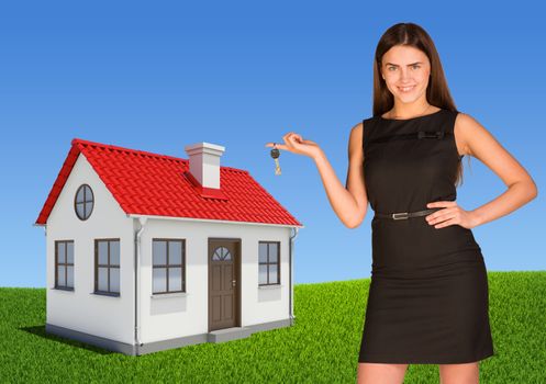 Businesswoman pointing at house, showing key. Green lawn and sky as backdrop