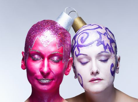 Two women with fantastic makeup posing as Christmas ornaments