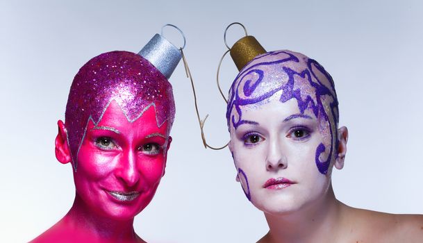 Two women with fantastic makeup posing as Christmas ornaments