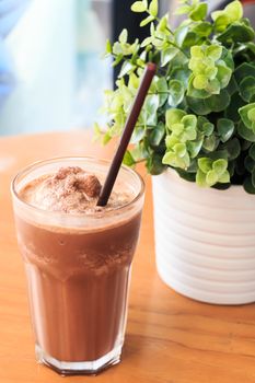 Cocoa milkshake on wood table with artificial plant