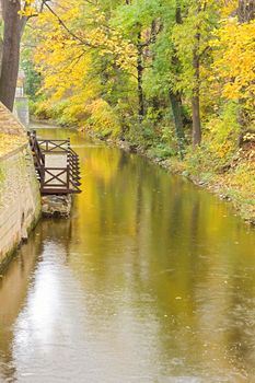 Photo shows a river and trees during the colourfull autumn.