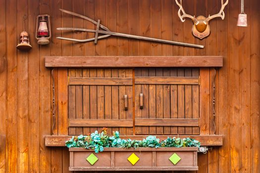 wood window on wood house and decorated with palnt,antler,lamp,bell and trident