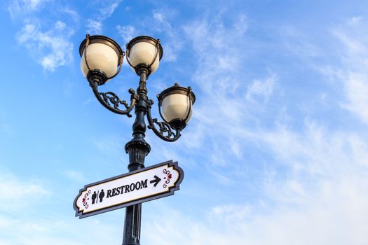 street lamp and signboard with text(restroom) on cloudy sky background