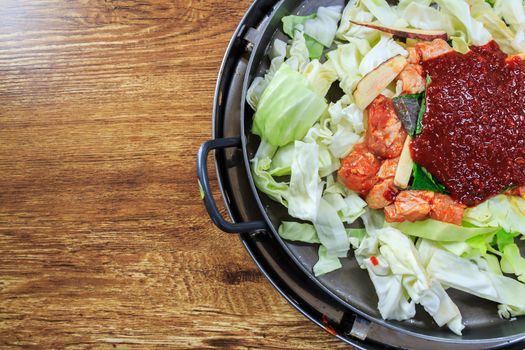 seasoning of korean food on pan compose of fresh lettuce,chicken,ketchup on wood table with blank area on left side