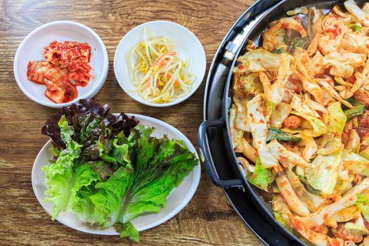 Korean food compose of kimchi,fresh lettuce, bean sprouts and stir-fried vegetables with chicken on wood table