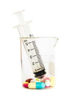 syringe in beaker and group of drugs on white background (isolated)