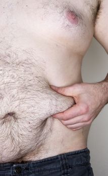 Image of a male grabbing his skin fat. Image is slightly cool 
