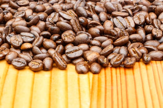 Close up of coffee beans on upper side and blank area at lower side on wooden table