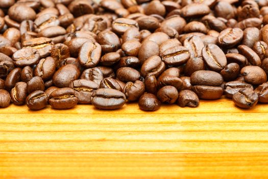 Close up of coffee beans on upper side and blank area at lower side on wooden table