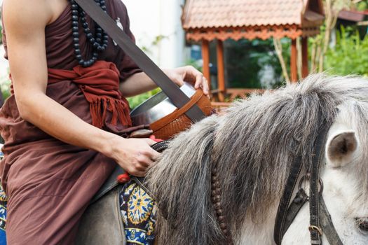 Buddhist monk with brown robe ride horse and ask for alms (Unseen in Thailand) at Chiangrai ,Thailand