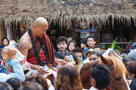 "Nauchai Kosito" (abbot of "Wild Cave Gold Horse Temple" ) ride brown horse and ask for alms (Unseen in Thailand) and many buddhist make merit at "Wild Cave Gold Horse Temple" in Chiangrai ,Thailand on December 31,2013