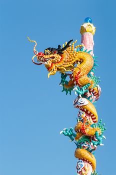 The old statue of gold dragon bind pillar and blue sky