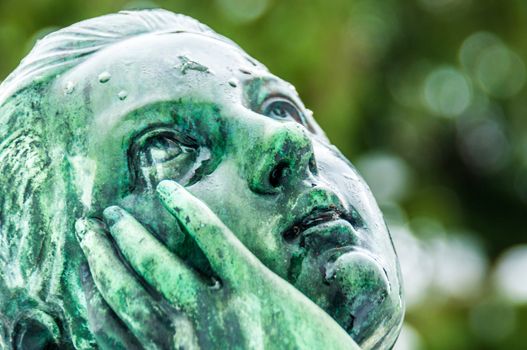 detail of a mourning sculpture on a cemetery