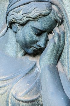 detail of a mourning sculpture on a cemetery