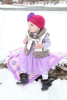 Little girl sitting on a log by the river