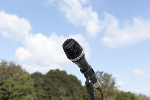 Microphone in focus against blurred trees and sky