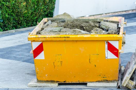 Gefüllter Container mit Bauschutt an einer Baustelle.