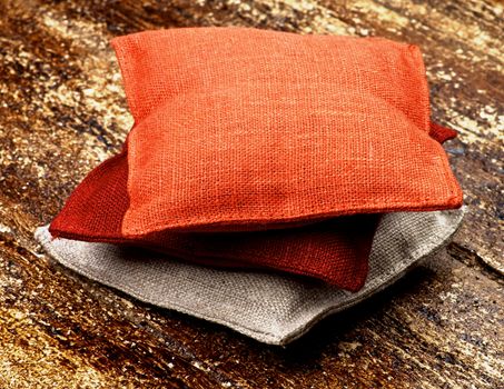 Stack of Three Textile Sachet Pillows closeup on Textured Wooden background