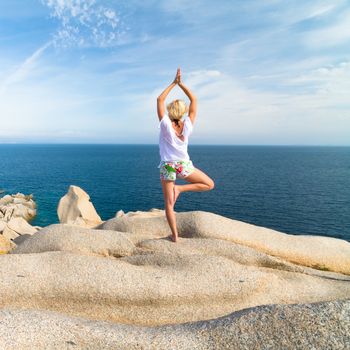 Sporty active woman practicing yoga at the beach.