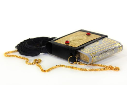 Quran with a cover and chain in front of white background