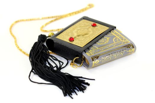 Quran with a cover and chain in front of white background