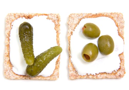 Canapes with gherkins and olives on a white background seen from above